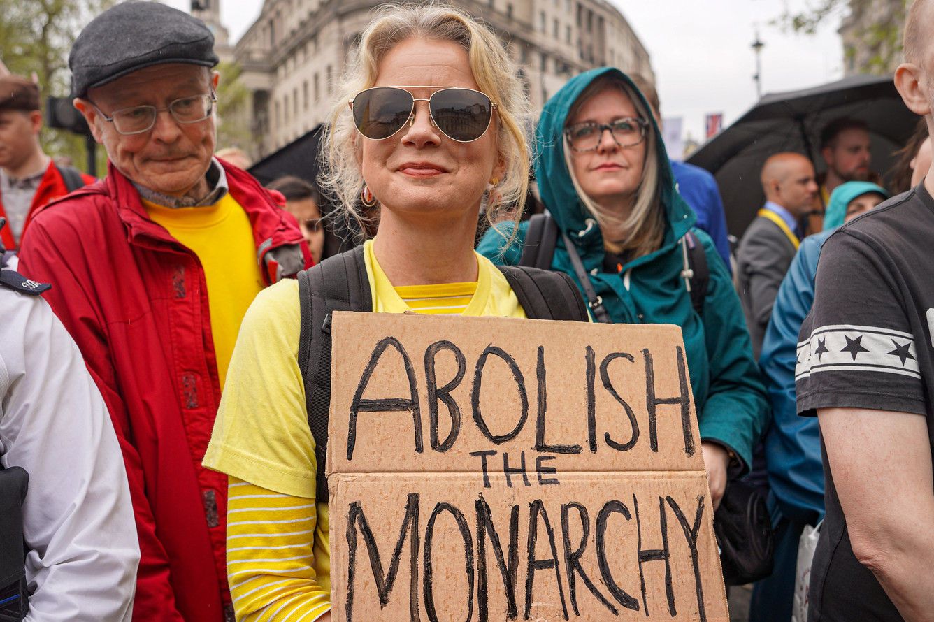 A protestor holds a "abolish the monarchy" sign